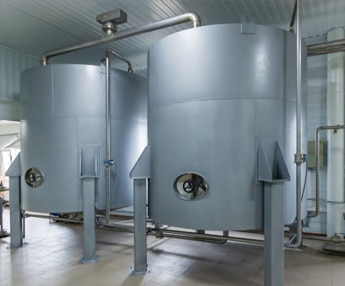 Industrial stainless steel water treatment tanks with connected piping system in a manufacturing facility